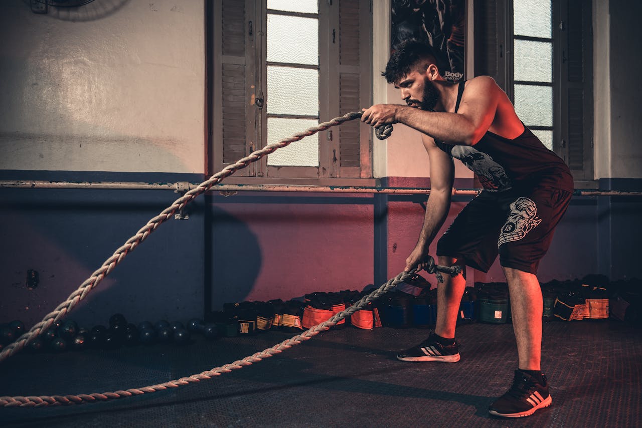 services-04 Man performing a challenging Crossfit rope exercise in an indoor gym setting.